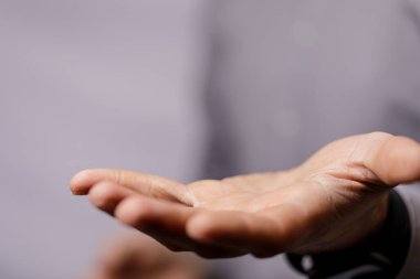 Açık el, uzanmış avuç içi elle tutulamaz, yumuşak gri bir arka plan sunuyor.