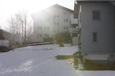 Binaların, karın ve güneş ışığının yansıttığı kış sahnesi.