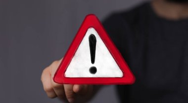 El ele tutuşan Kırmızı Uyarı Üçgeni Uyarı İşareti