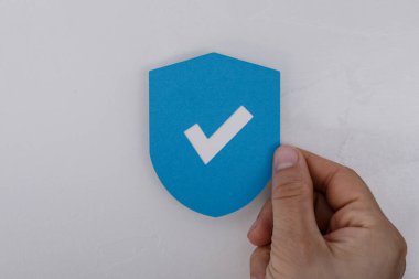 Elinde işaretli mavi bir kalkan sembolü var.