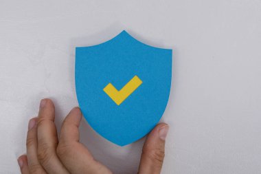 Beyaz Arkaplanda İşaretli Mavi Kalkan Elle Tutuluyor