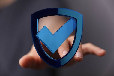 Elinde mavi bir kalkan var. Güvenlik ve onay işareti var.