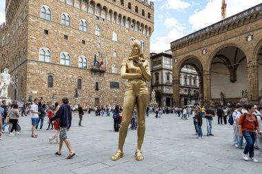 Florence, Italy - May 10th, 2025: Time Unfolding, a golden bronze sculpture by Thomas J Price, stands in Piazza della Signoria near Palazzo Vecchio