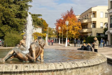 Abano Terme, İtalya - 29 Ekim 2025: Fıskiye heykelleri ve sonbahar boyunca şehir merkezinde yürüyen insanların manzarası