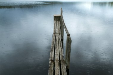 Çek doğasında göletin yüzeyindeki eski ahşap iskele güzel bir yağmurla bulutlu bir günde. 