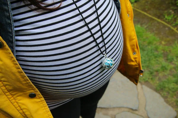 为支持婴儿听力发育 带有铃铛或墨西哥波纹的孕妇腹部的细节 — 图库照片