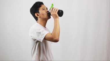 Siyah şişe tutan Asyalı adam beyaz arka planda izole edilmiş kas geliştiren protein takviyesi içiyor.