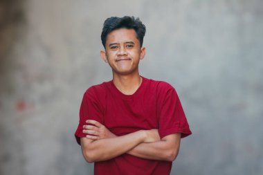 Asyalı bir adam kollarını kavuşturup gülümsüyor.