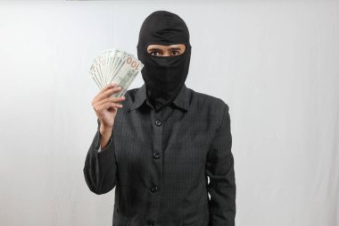 Kar maskesi takan ve takım elbiseli bir adam yüz dolarlık banknotlar tutuyor..