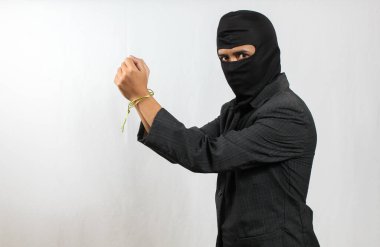 Maske takan hırsız ve siyah takım elbiseli yakalanmış. Beyaz arka planda küçük bir iple bağlanmış.