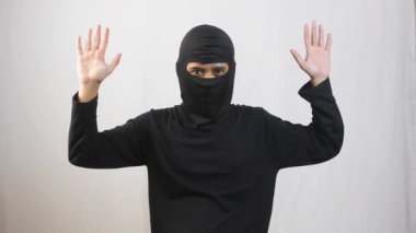Siyah maskeli bir hırsız teslim olmak için iki elini de kaldırdı.