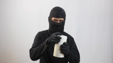 Hırsız her yöne baktı ve içinde dolar koleksiyonu olan plastik kavanozu açtı..