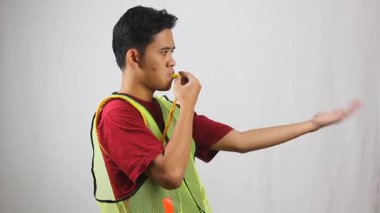 Park görevlisi, düdük çalarken elini öne doğru sallayarak aracın yavaşça ilerlemesini sağlar..