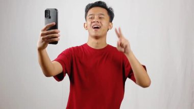 Elinde akıllı telefon tutan Asyalı bir adam samimi bir şekilde selfie çekiyor.