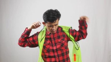 İnşaat alanına girmeden önce yelek ve şapka takan bir adam.