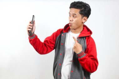 Kapüşonlu Asyalı adam akıllı telefon kullanarak selfie çekiyor.