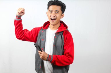 Heyecanlı genç adam telefonda güzel haberleri kutluyor. Hevesle gülümsüyor. Olumlu yaşam tarzı ve başarı temaları için mükemmel.