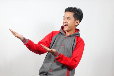 Gri ve kırmızı takım ceketli gülümseyen genç adam beyaz arka planda fotokopi alanına doğru hareket ediyor.