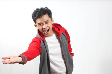 Kırmızı ve gri takım ceketli gülümseyen Asyalı adam açık el hareketleriyle bir şey sunar..