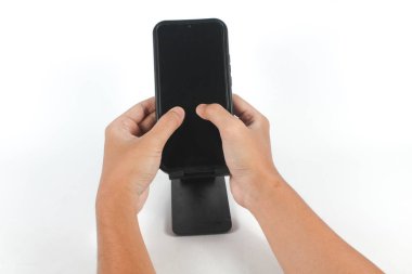 İki el de cep telefonunu tutarak, tutacağına bağlı olarak boş ekrana başparmaklarıyla dokunuyor.