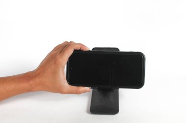 Tutucuya bağlı olan cep telefonunun hoparlör düğmesine basıyorum.