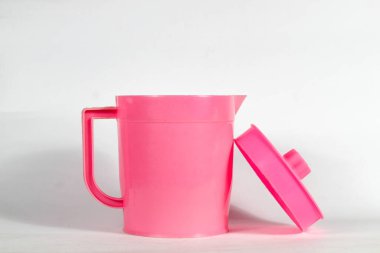 Açık kapaklı pembe plastik çaydanlık beyaz arkaplanda izole edilmiş.