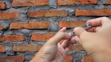 Tırnak makası ile uzun tırnakları kesme aktivitesi tuğla duvar arka planında