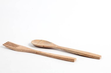 Tahtadan yapılmış kaşıklar ve çatallar beyaz arka planda izole edilmiş. Köy hissi veren geleneksel çatal bıçak takımı.