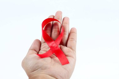 Aralık ayında Dünya AIDS Günü için kırmızı kurdele tutan eller beyaz arka planda izole edilmiş. AIDS hastalığına karşı sağlık kavramı.