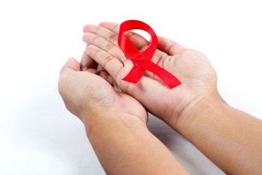 Dünya AIDS Günü 'nü simgeleyen kırmızı bir kurdele tutuyor.