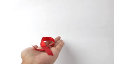Dünya AIDS Günü anısına izole edilmiş beyaz arka planlara kırmızı kurdele tutan eller.