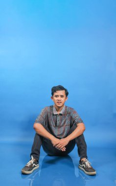 Mavi Arkaplanda Oturan Genç Adamın Rastgele Rahatlamış Portresi