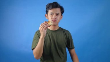 Asyalı bir adam karnını doyurana kadar hamburger yiyor. Bu da kendini mavi arka planda tamamen soyutlanmış hissettiriyor.