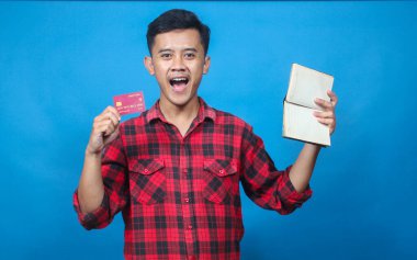 Asyalı adam kredi kartı tutuyor ve boş tasarruf defteri gösteriyor