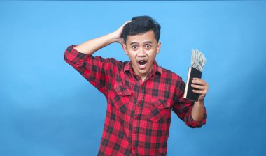 Asyalı adam kafasını kaşıyarak içinde para olan bir tasarruf kitabı tutuyor.