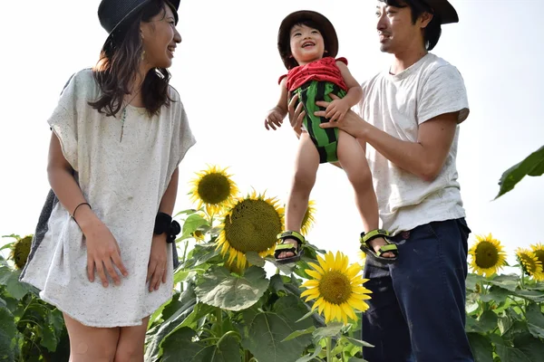 年轻的家庭微笑与向日葵字段 — 图库照片