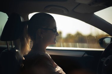 Araba kullanan kadın portresi. Güneş gözlüğü takıyor..