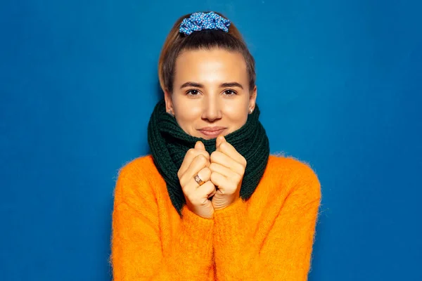 蓝色背景下身穿橙色毛衣和绿色围巾的少女的画像 — 图库照片