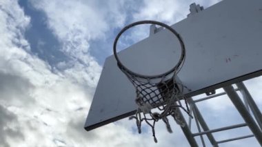 Gökyüzünün arka planında bulutlu terk edilmiş basketbol çemberinin dramatik manzarası.