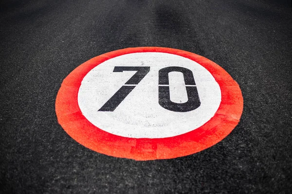 暗いアスファルトの道路上に描かれた毎時70キロの速度制限記号 — ストック写真