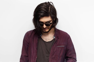 Beyaz arka planda güneş gözlüklü hippi bir gencin portresi..