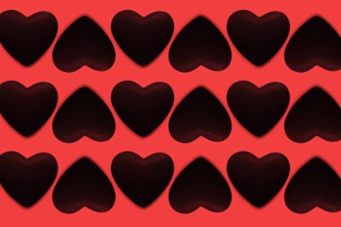 Kırmızı arkaplanda siyah kalplerin deseni.