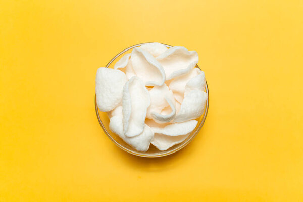 Top view of white chips in bowl on yellow background.