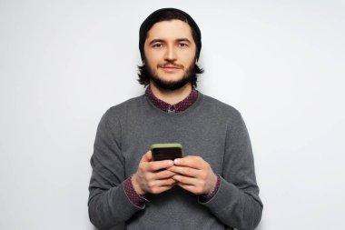 Beyaz arka planda akıllı telefonlu bir gencin stüdyo portresi..