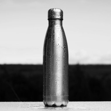 Siyah beyaz fotoğraf, termo şişeye yakın çekim, su püskürtülmüş..