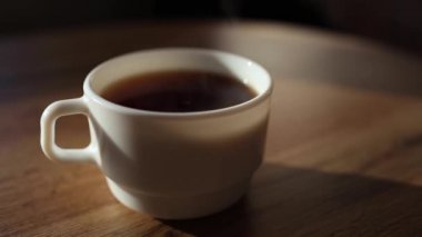 Kadın elinin yakın çekimi beyaz bardakta çayı karıştırır..