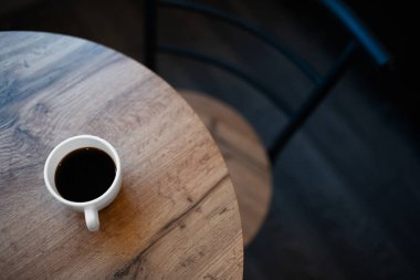 Kafeterya konsepti. Açık kahverengi ahşap masada küçük beyaz bir fincan espresso.. 