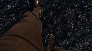 Siyah ayakkabılı adam kara toprak yolunda yürüyor. Erkek bacaklarının üst görüntüsü.