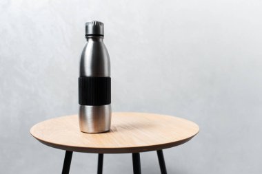 Close-up of steel reusable thermo water bottle on wooden table.
