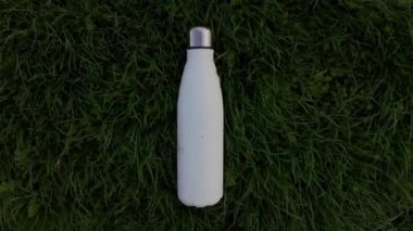 Yeniden kullanılabilir, eko-çelik termodinamik su şişesi yeşil çimlerin üzerinde rüzgarlı bir günde.